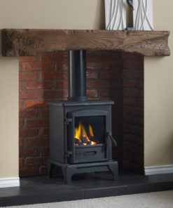 A wood burning stove heats a living room under a rustic wooden mantel